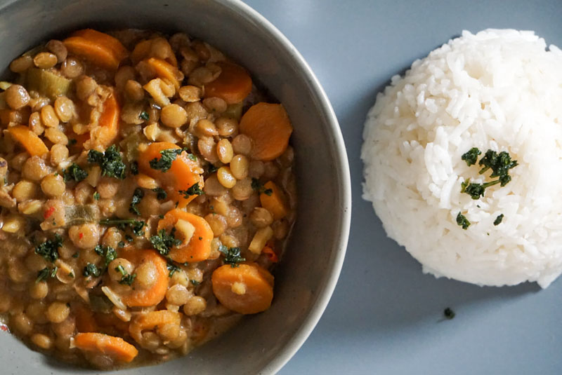 Nahuafnahme Eine Schale mit Kokos-Linsen-Curry, dazu Reis