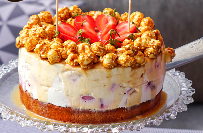 Erdbeer-Torte mit Karamell und Popcorn, auf gartentisch, Topping im Fokus