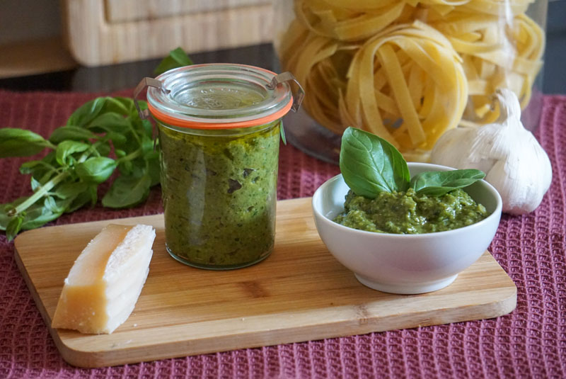 Einfaches Pesto verde in Schälchen und im Weckglas, daneben Nudeln, Basilikum und Knoblauch