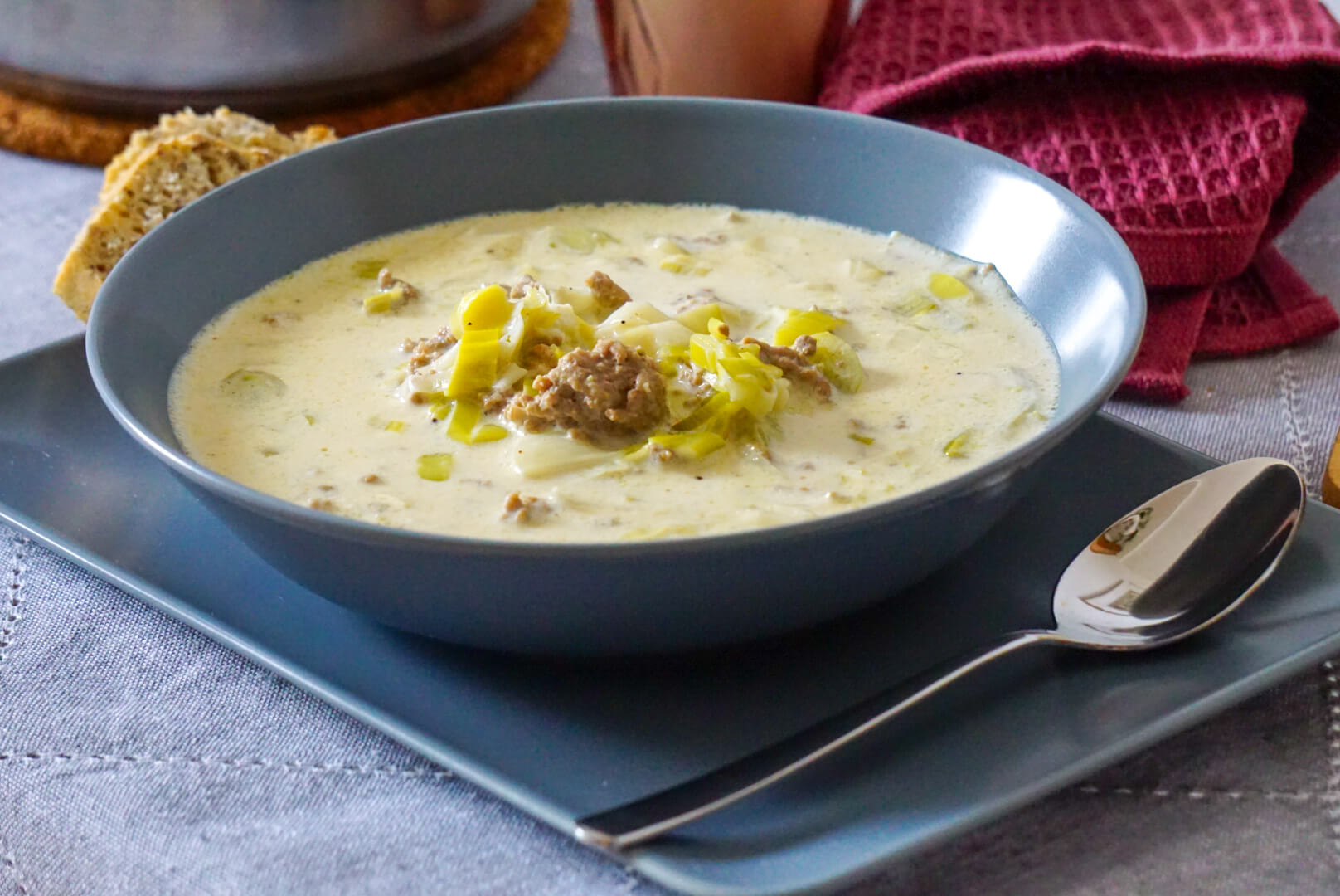 Ein Teller mit Käse-Lauch-Suppe daneben ein Stück Brot