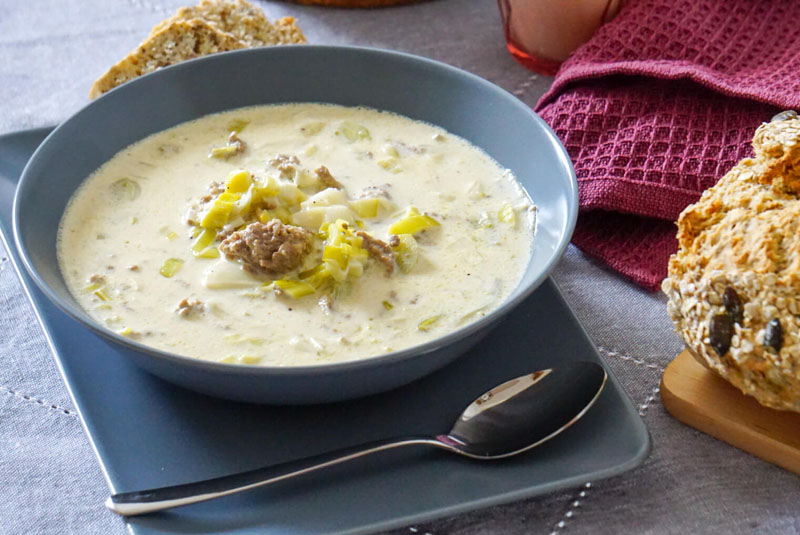 Ein Teller mit Käse-Lauch-Suppe daneben ein Stück Brot